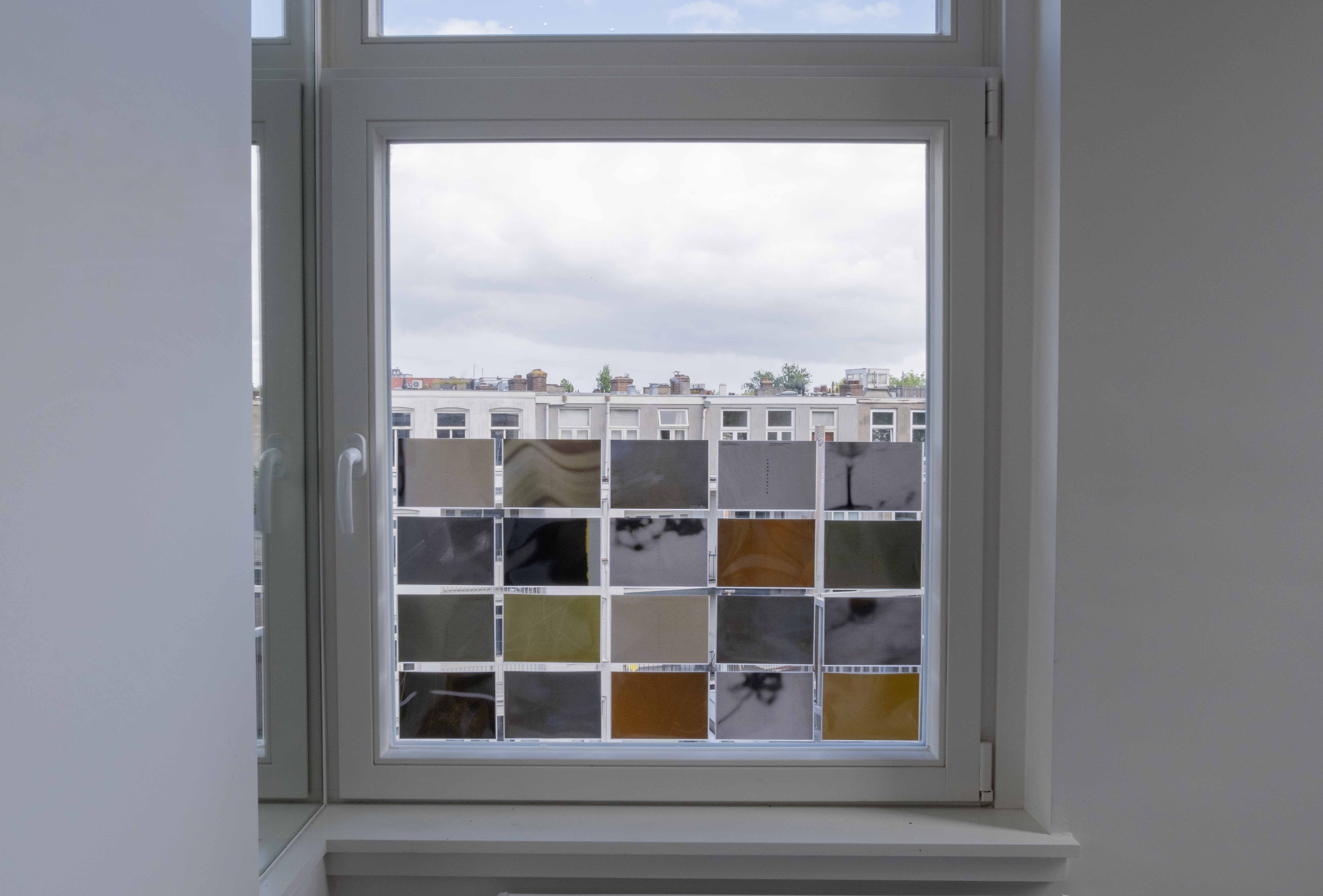 A grid of postcards on a window